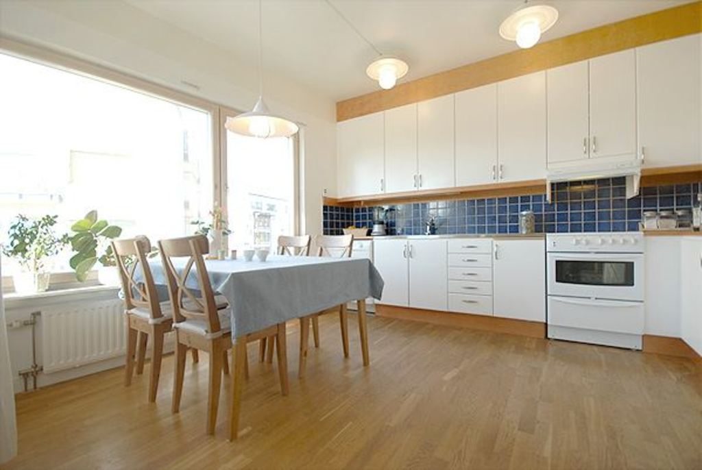 Light-filled kitchen and dining space with a long table and white cabinets