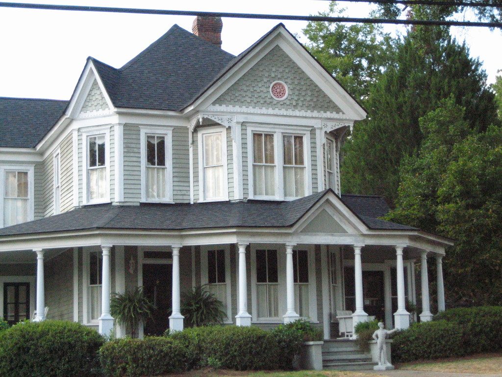 Victorian home with a wraparound porch and grey roof
