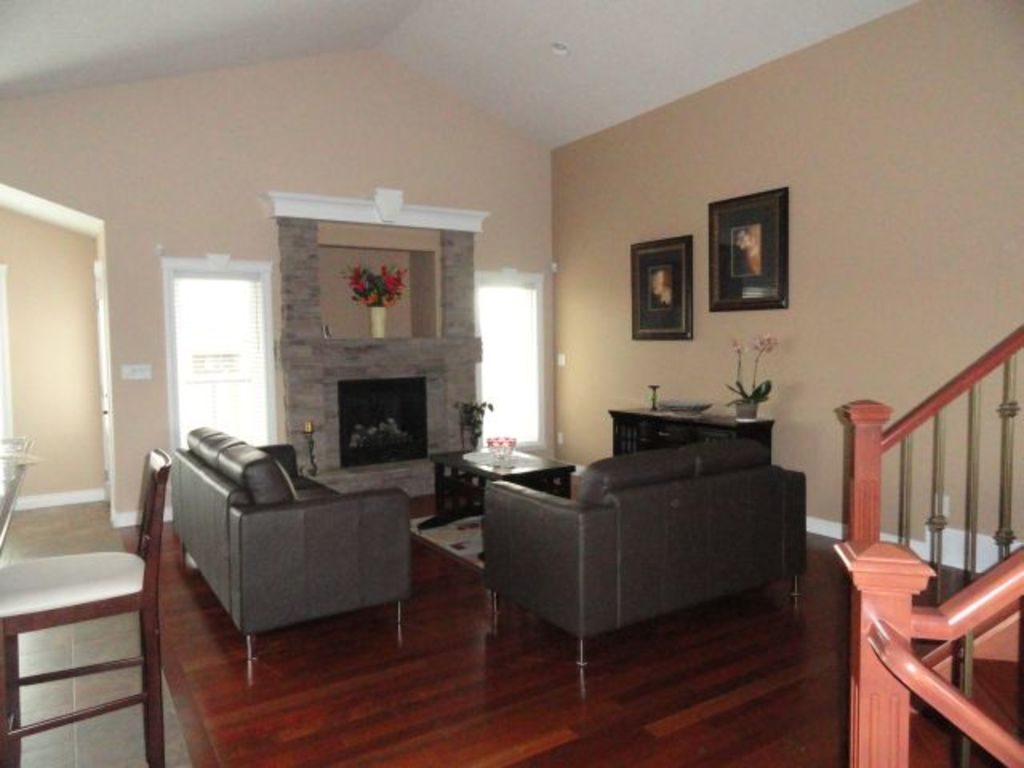 Bright living room with a stone fireplace, leather sofas and warm wood floors
